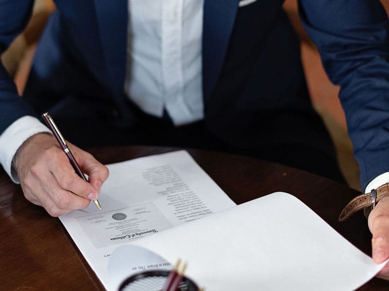 Corporate service providers: A professional signing company documents. Photo by Mikhail Nilov on Pexels.